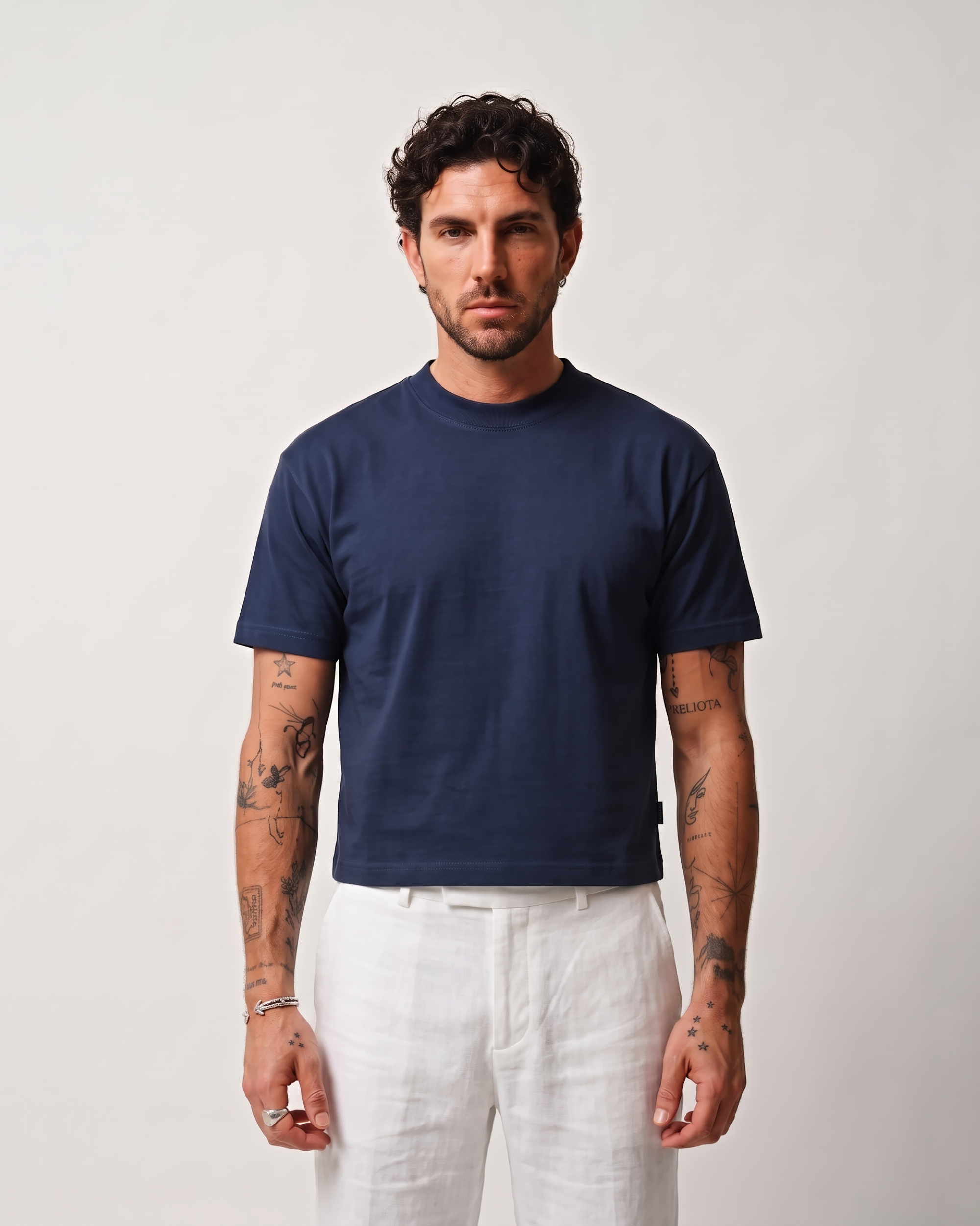 Front view of a model wearing a navy blue boxy fit T-shirt with white trousers