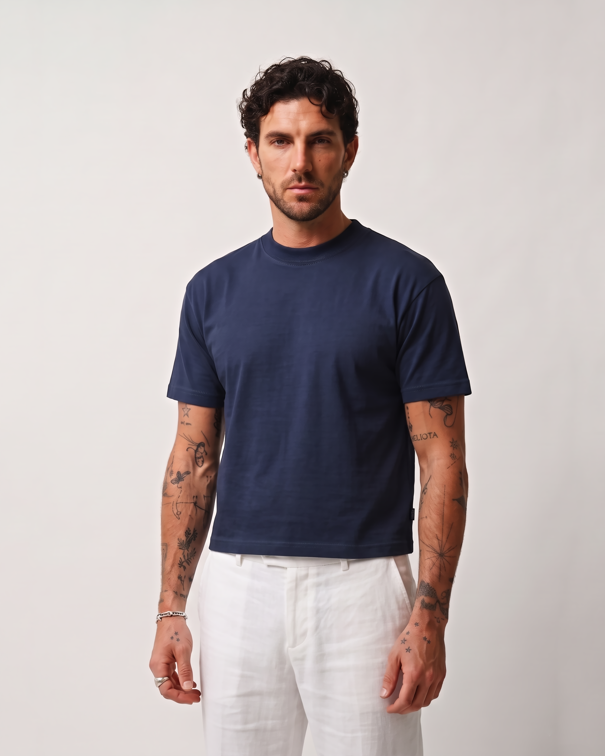 Model wearing a navy blue boxy fit T-shirt with white trousers, quarter pose