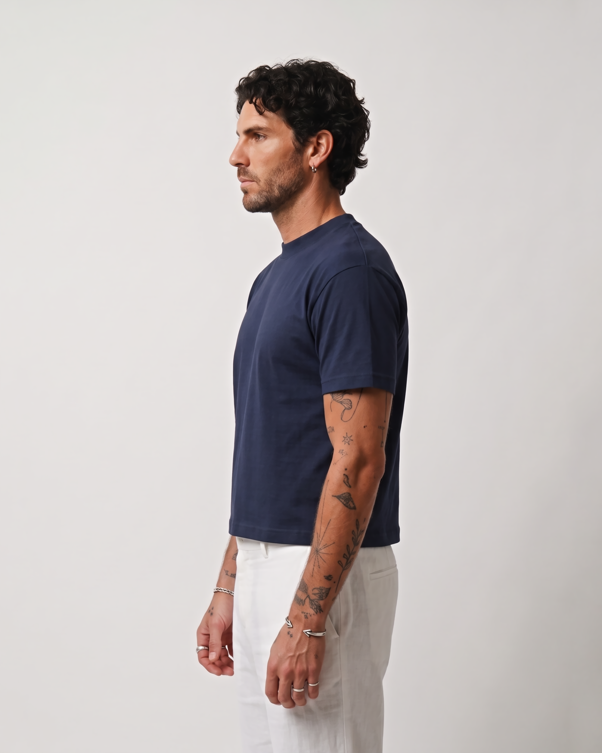 Side profile of a model wearing a navy blue boxy fit T-shirt with white trousers