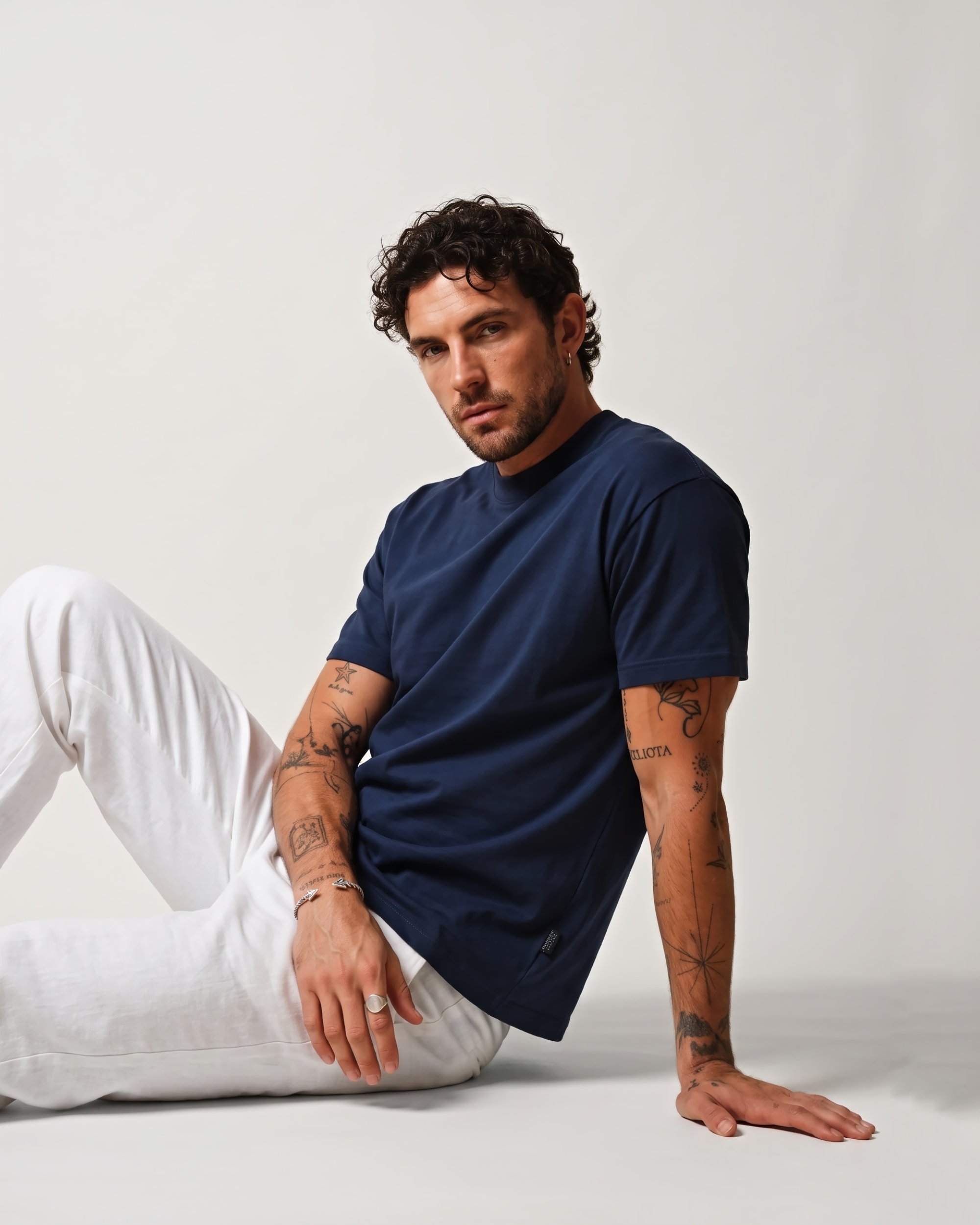 Model wearing a navy blue boxy fit T-shirt and white trousers in a seated pose