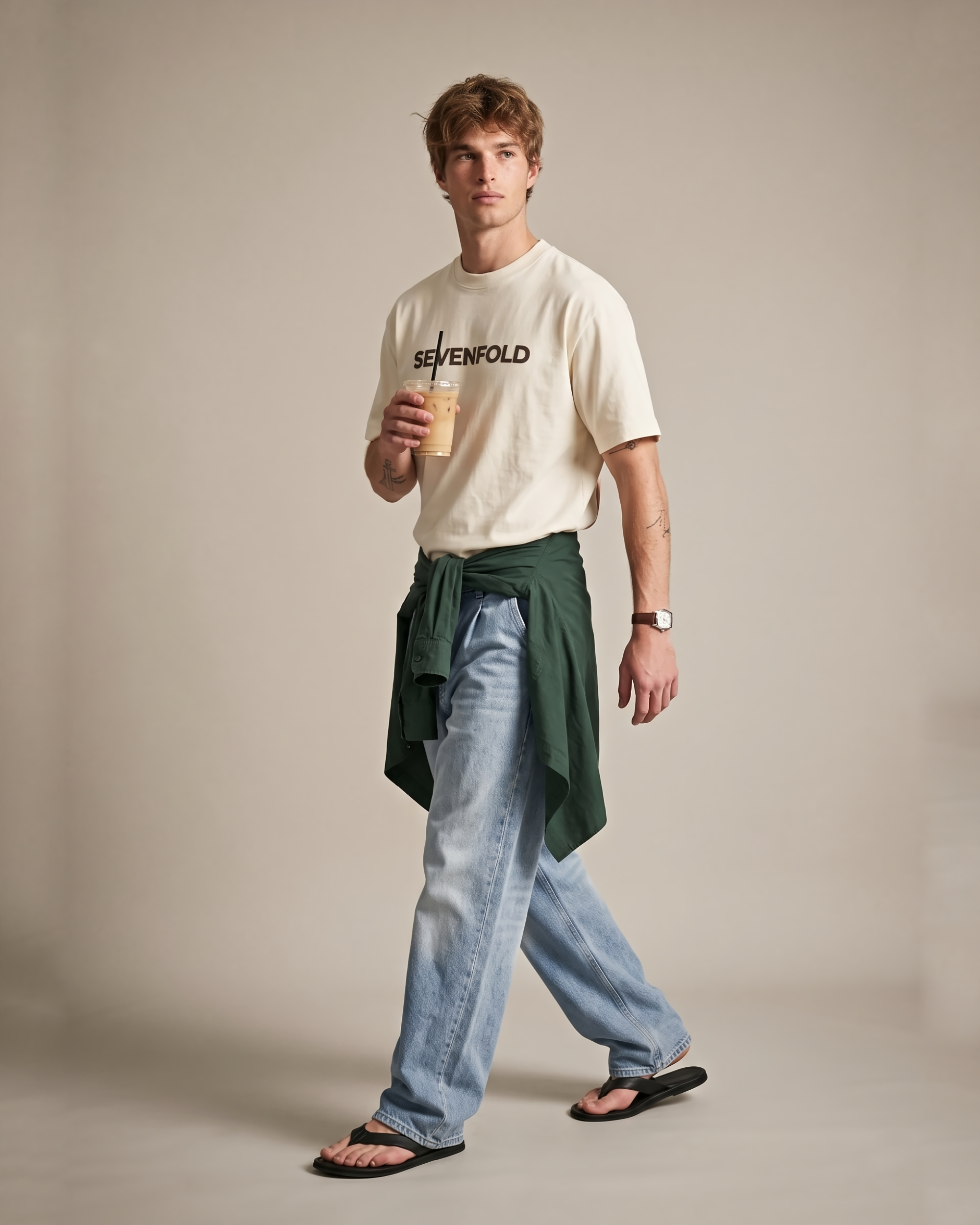 Side quarter view of a model wearing a SEVENFOLD ivory logo T-shirt with relaxed blue jeans