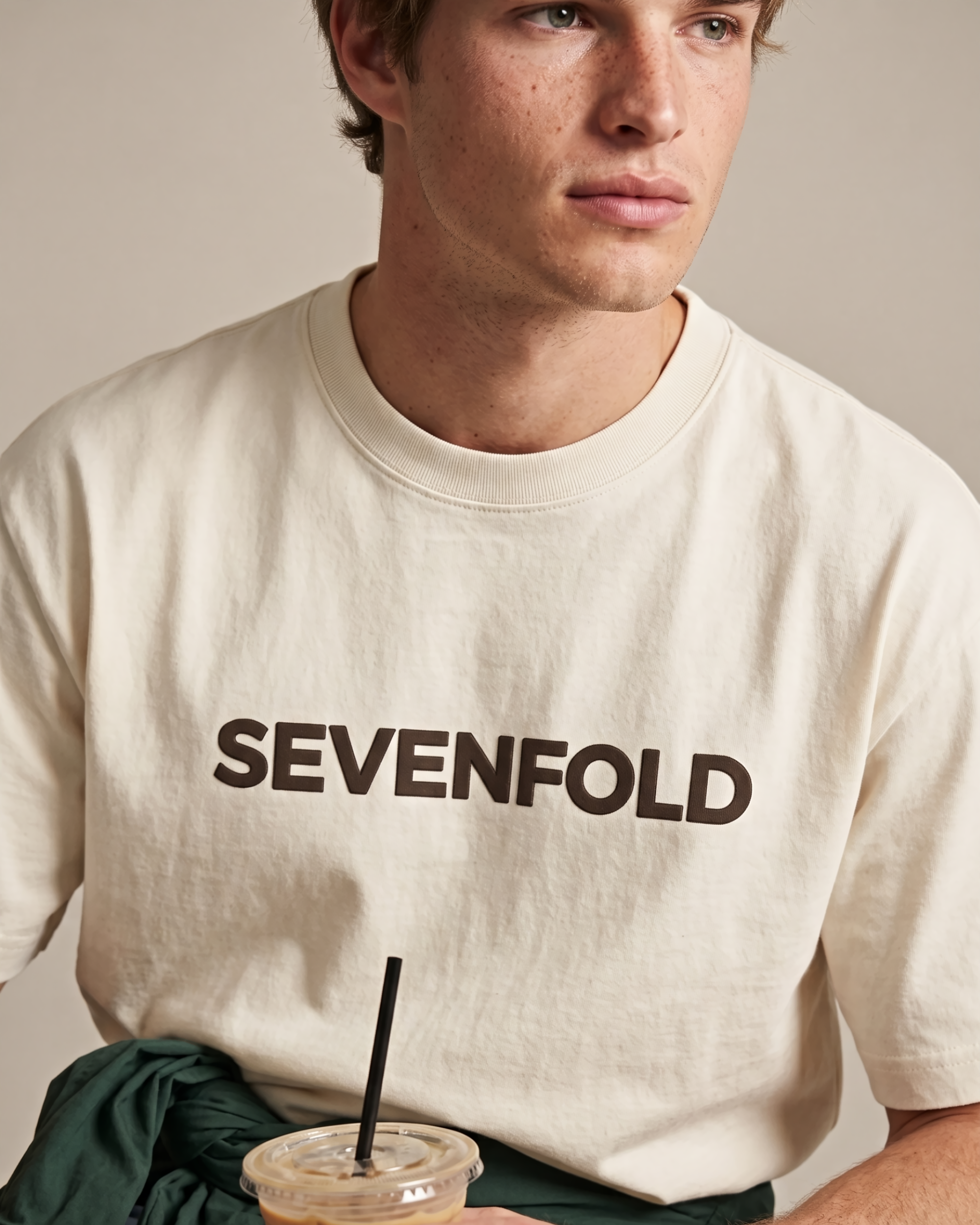 Close-up of the dark SEVENFOLD logo printed on an ivory T-shirt